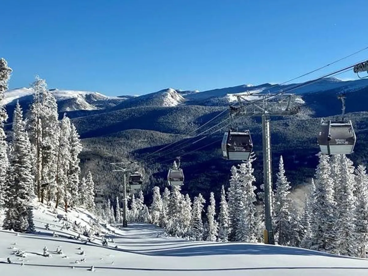A vibrant winter scene featuring ski lift gondolas gliding above snow-covered mountains and a dense pine forest. Adventurers can be seen preparing for or returning from an exhilarating day on the slopes, with the mountain range stretching into the distance and hints of blue sky peeking through.