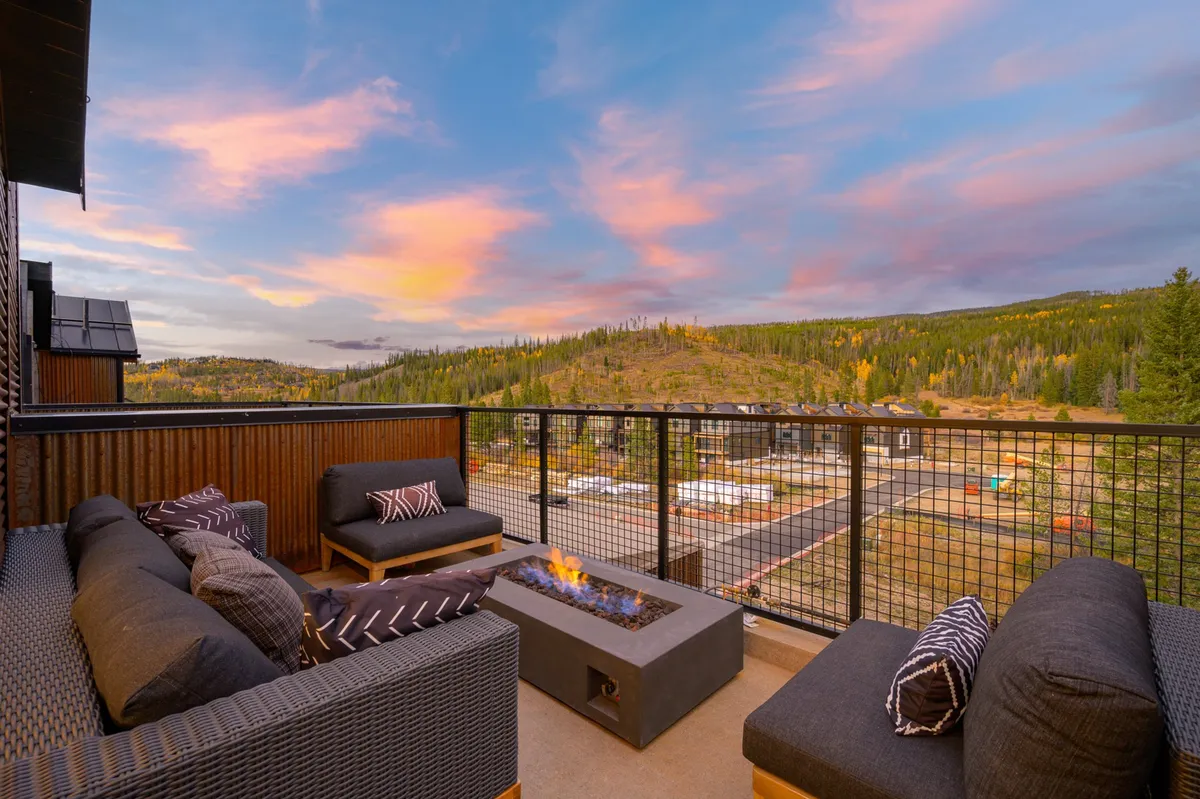 A cozy exterior setting featuring a fire pit surrounded by comfortable outdoor seating, all set against a stunning mountain backdrop. The space is clearly designed for gatherings, relaxation, and taking in the natural beauty—great for pets and families alike.