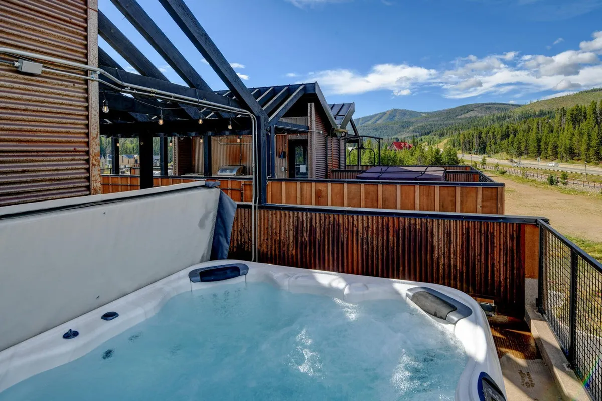 An inviting wooden deck with a private hot tub overlooking the mountains, surrounded by fresh air and natural beauty. The setting is ideal for unwinding after a day packed with adventure, with the possibility of stargazing or sharing stories with friends.